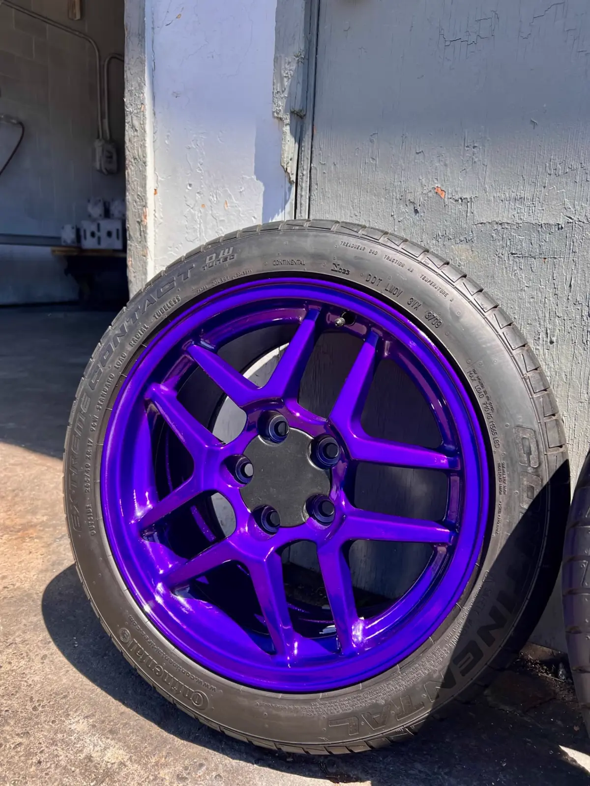 Set of Corvette Z06 wheels powder coated in candy purple over a black base, lined up outside the North Vancouver shop