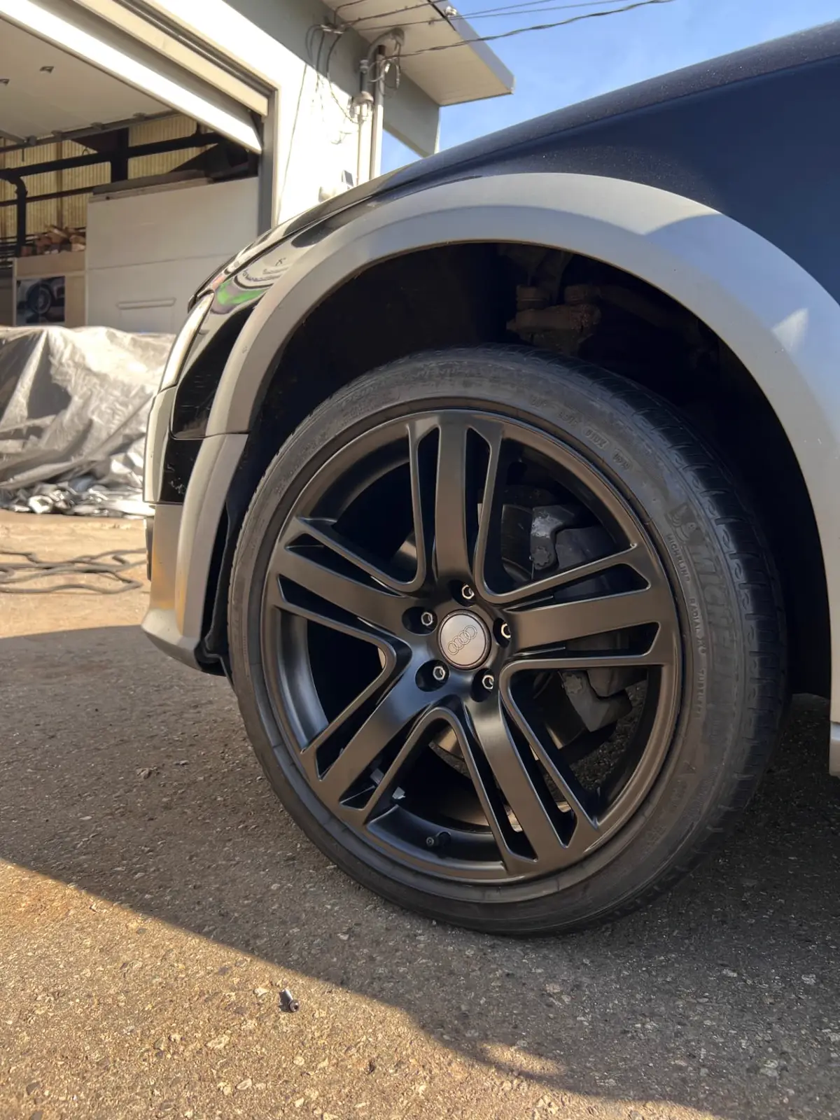 Audi Q7 wheel powder coated satin black installed on a blue Audi outside the North Vancouver workshop
