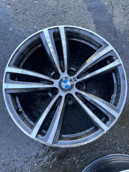 Curb-rashed BMW alloy wheel showing deep gouges and worn factory finish before restoration at Superior Powder Coatings North Vancouver
