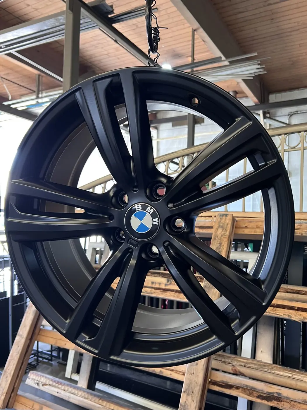 Same BMW alloy wheel after sandblast prep and matte black powder coating — flawless oven-cured finish