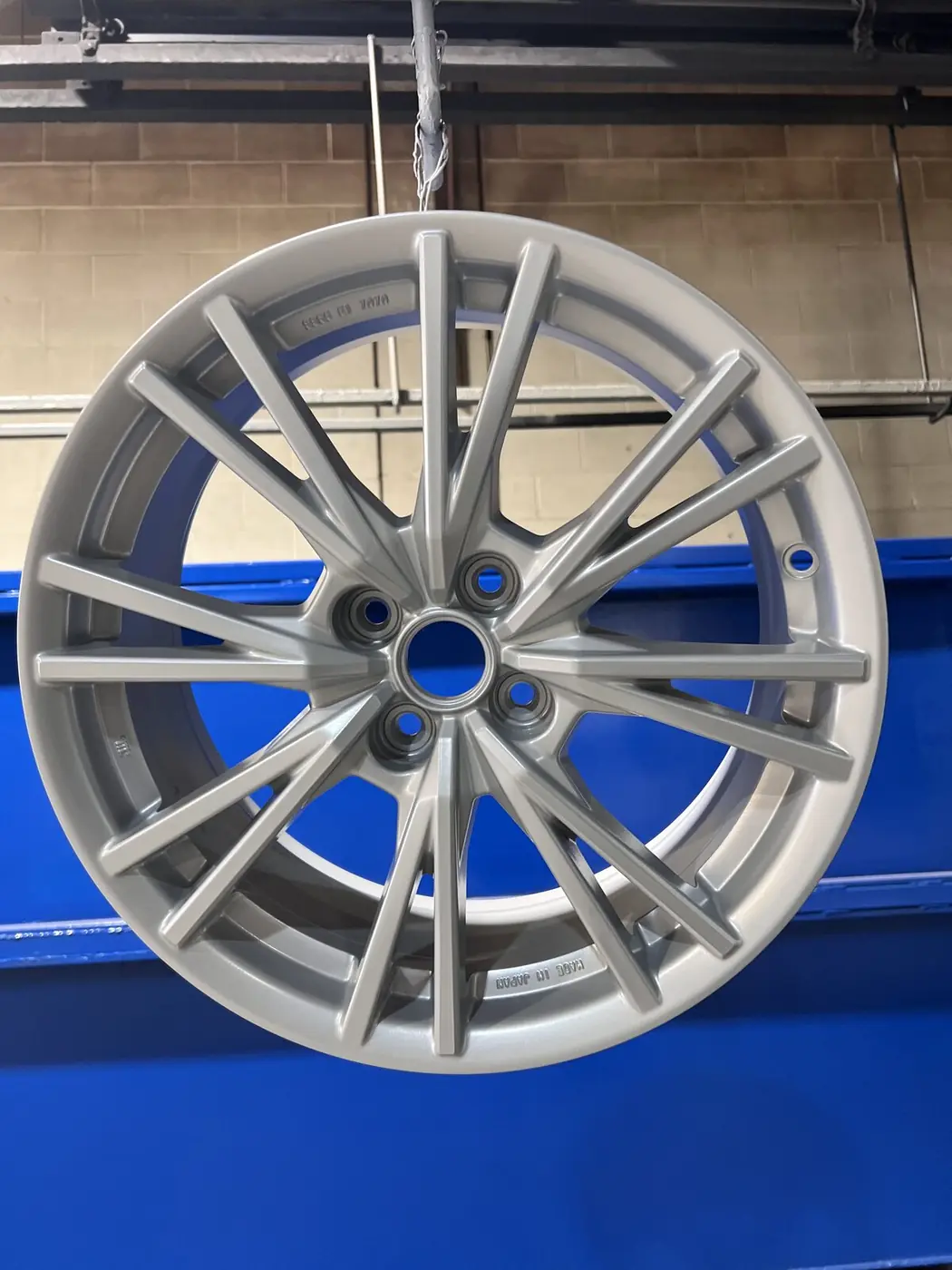 Hyper silver powder coated Lexus alloy wheel hanging in the powder coating booth at 360 Lynn Ave, North Vancouver