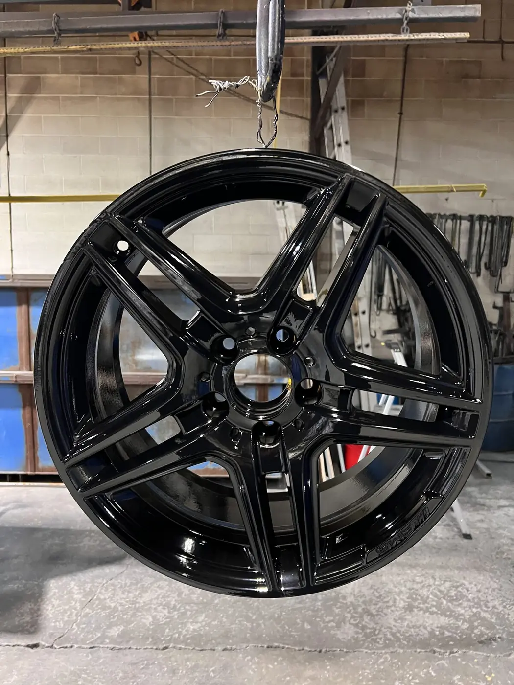 Gloss black powder coated Mercedes-Benz AMG alloy wheel freshly cured in the powder coating booth